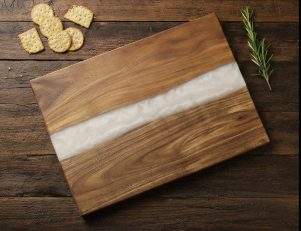 Wooden cutting board with a white center on a wooden surface with crackers and rosemary.